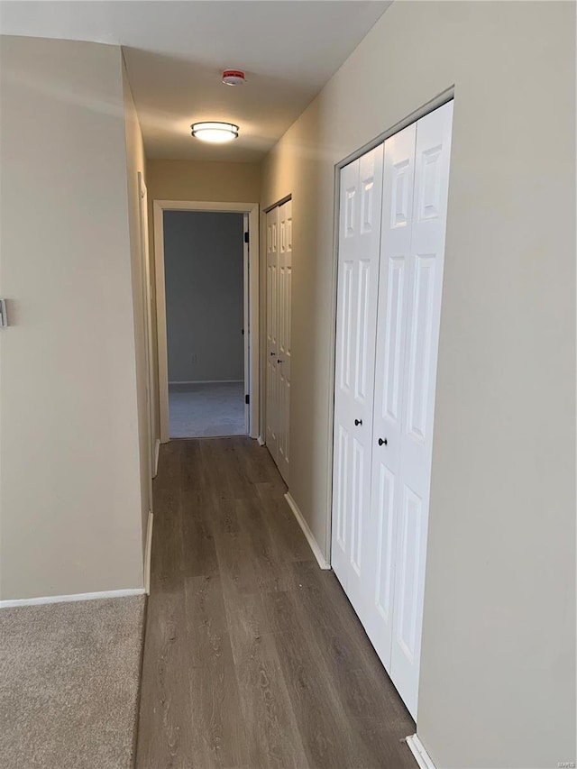 hallway with dark wood finished floors and baseboards