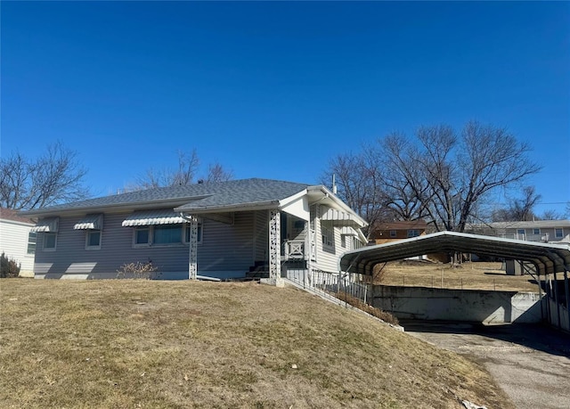 view of home's exterior featuring aphalt driveway, a detached carport, a lawn, and a shingled roof