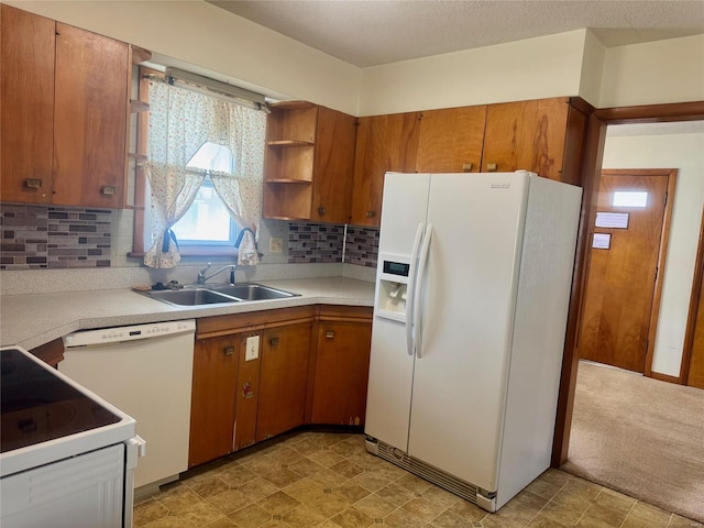 kitchen with light countertops, white appliances, a sink, and brown cabinets