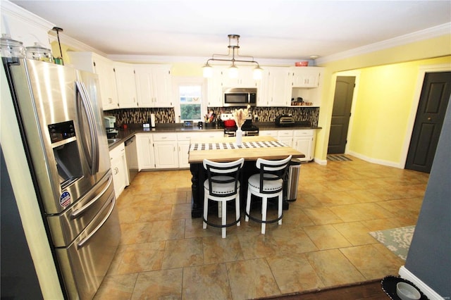 kitchen featuring stainless steel appliances, dark countertops, ornamental molding, and tasteful backsplash