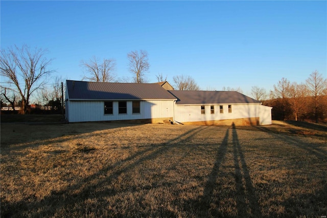 rear view of house featuring metal roof and a yard