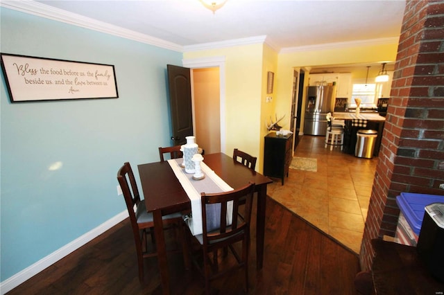 dining space featuring baseboards, crown molding, and wood finished floors