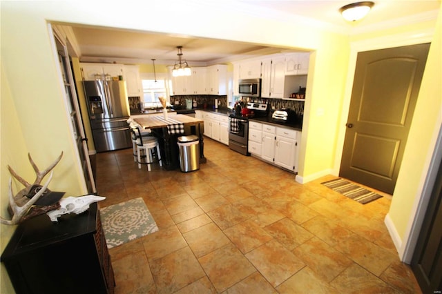 kitchen with white cabinets, a kitchen island, stainless steel appliances, crown molding, and backsplash