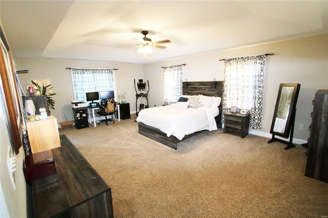 carpeted bedroom with a raised ceiling, ceiling fan, and baseboards