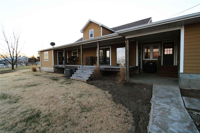 back of property featuring a porch, a lawn, and central air condition unit