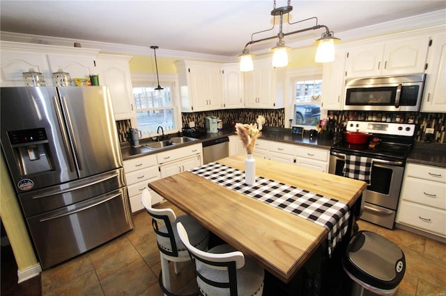 kitchen with stainless steel appliances, a sink, white cabinets, a wealth of natural light, and decorative backsplash