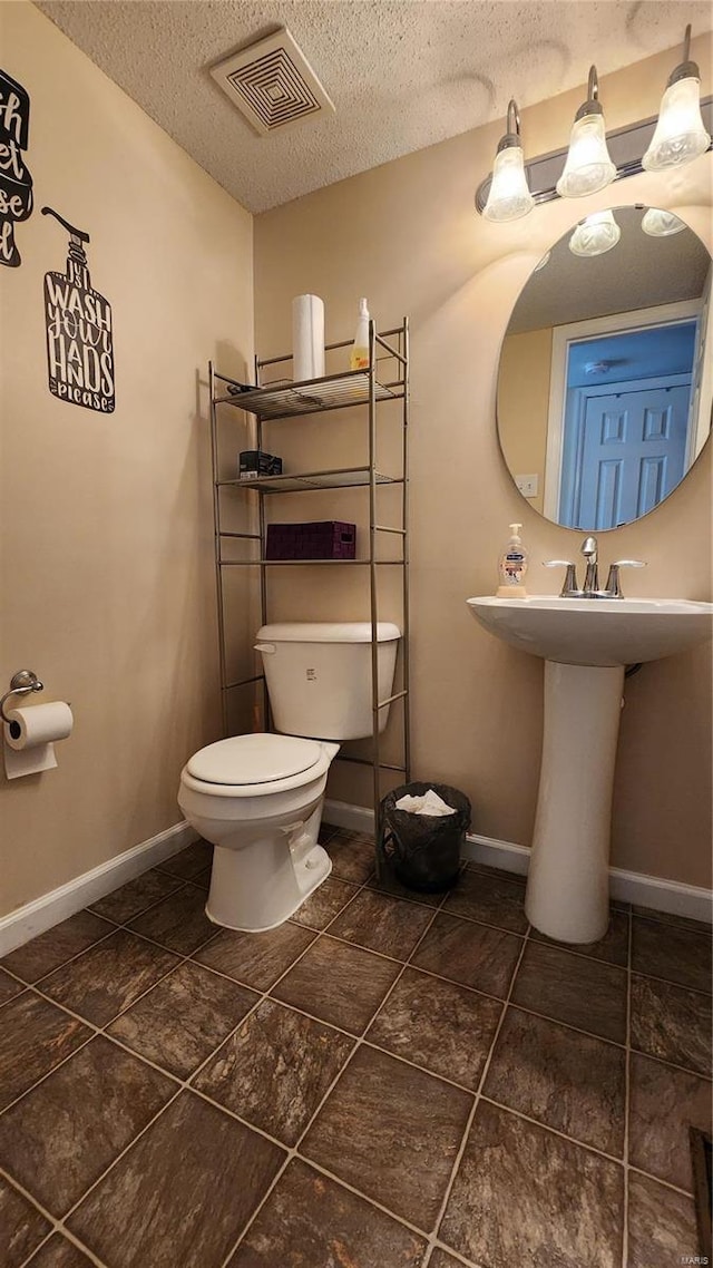 bathroom featuring visible vents, a textured ceiling, toilet, and baseboards