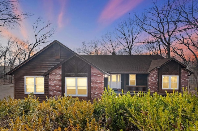 view of front of home with brick siding and roof with shingles