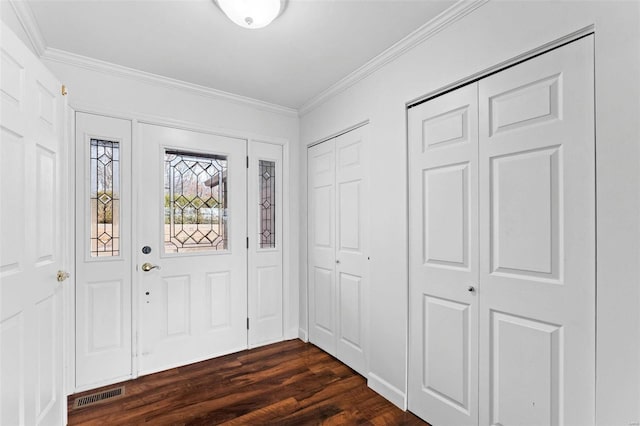 foyer entrance with ornamental molding, visible vents, and dark wood-style floors