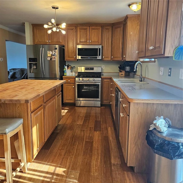 kitchen with dark wood finished floors, crown molding, stainless steel appliances, wooden counters, and a sink