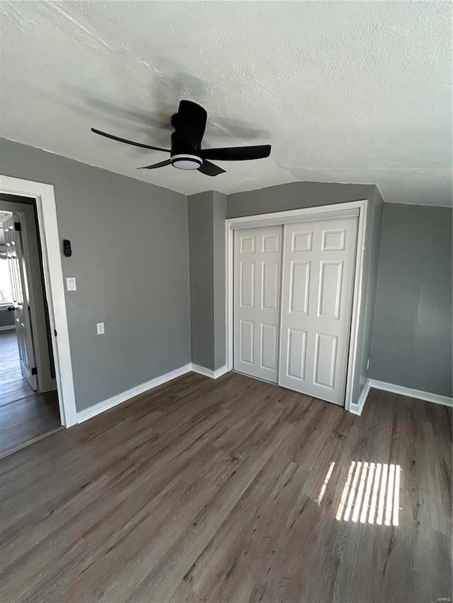 unfurnished bedroom featuring a textured ceiling, a closet, baseboards, and wood finished floors