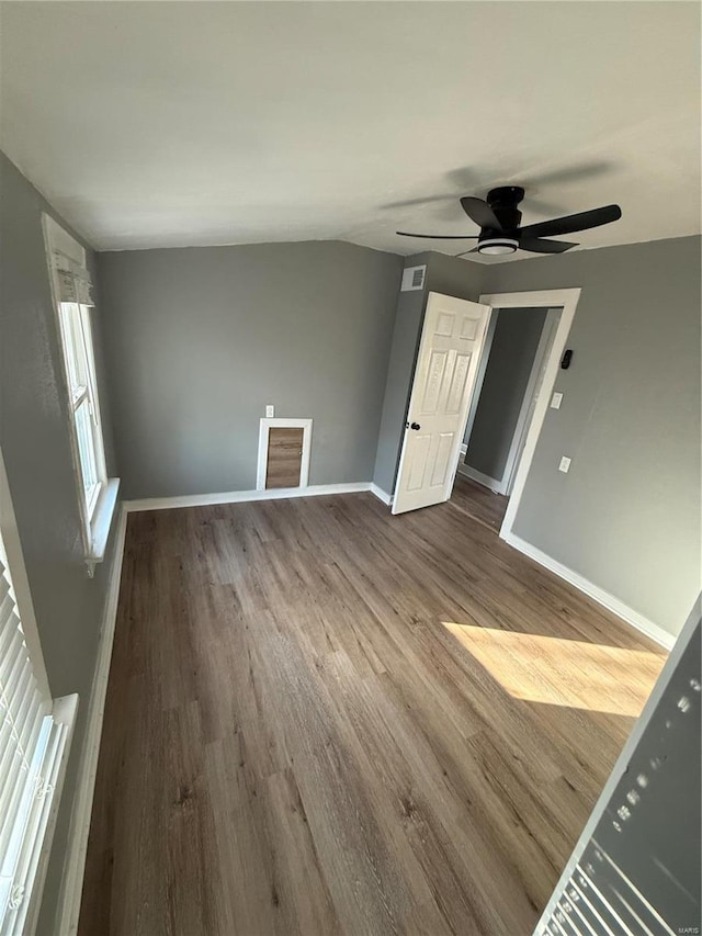 interior space featuring a ceiling fan, visible vents, baseboards, and wood finished floors