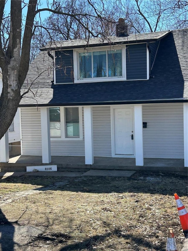 view of front of home with a chimney and roof with shingles