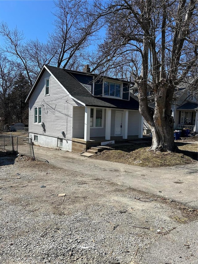 view of front of house featuring driveway, a shingled roof, a chimney, and fence