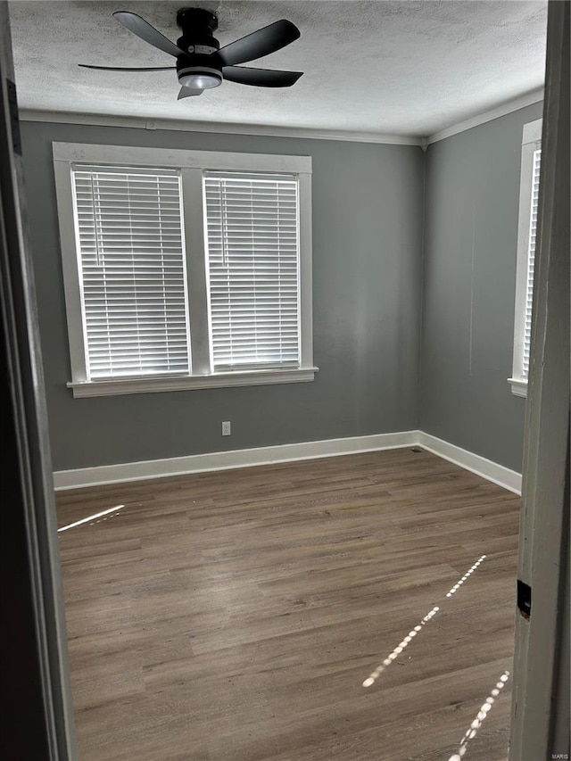 empty room featuring a textured ceiling, ceiling fan, wood finished floors, and baseboards