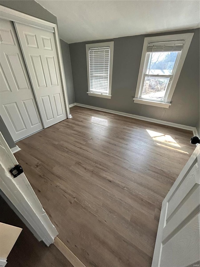 unfurnished bedroom with a closet, baseboards, and wood finished floors