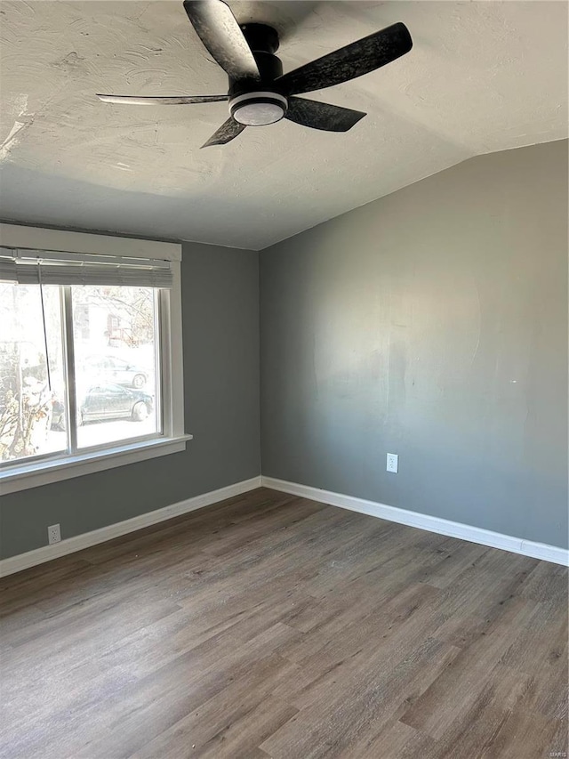 spare room featuring a textured ceiling, wood finished floors, and baseboards