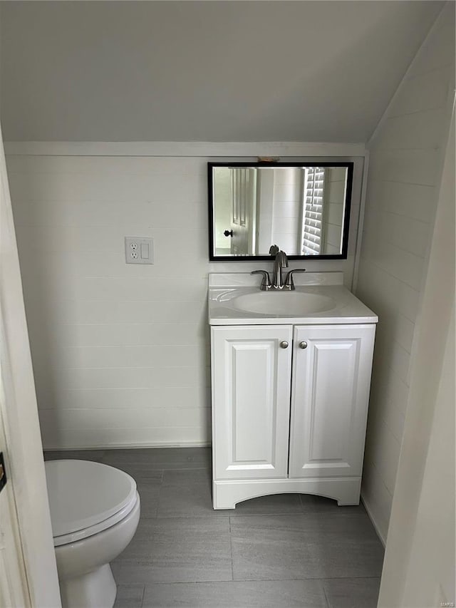 bathroom with vaulted ceiling, vanity, and toilet