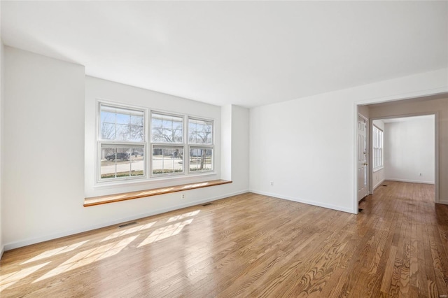 empty room featuring visible vents, baseboards, and wood finished floors