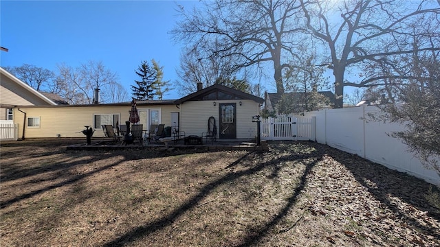 rear view of property with a patio area, fence, and a gate