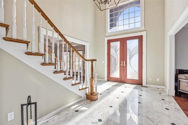 foyer featuring baseboards, a towering ceiling, stairway, marble finish floor, and french doors