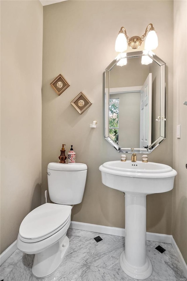 half bathroom featuring marble finish floor, toilet, and baseboards