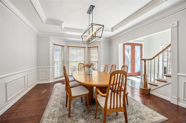 dining area featuring a raised ceiling, a decorative wall, stairway, wainscoting, and hardwood / wood-style flooring