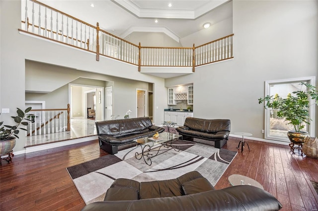 living area with ornamental molding, hardwood / wood-style floors, stairway, and baseboards