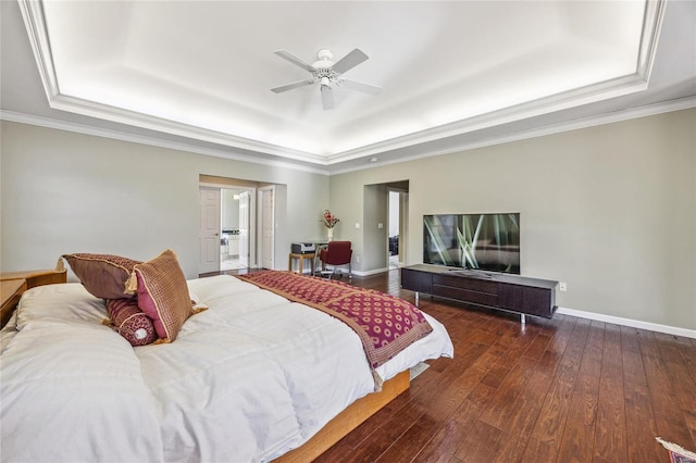 bedroom with wood-type flooring, a tray ceiling, and baseboards