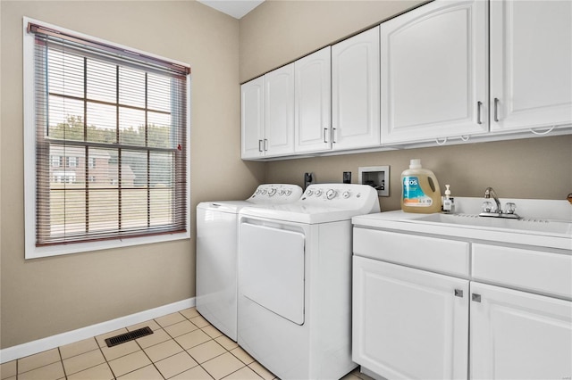 washroom featuring cabinet space, baseboards, visible vents, washing machine and clothes dryer, and a sink