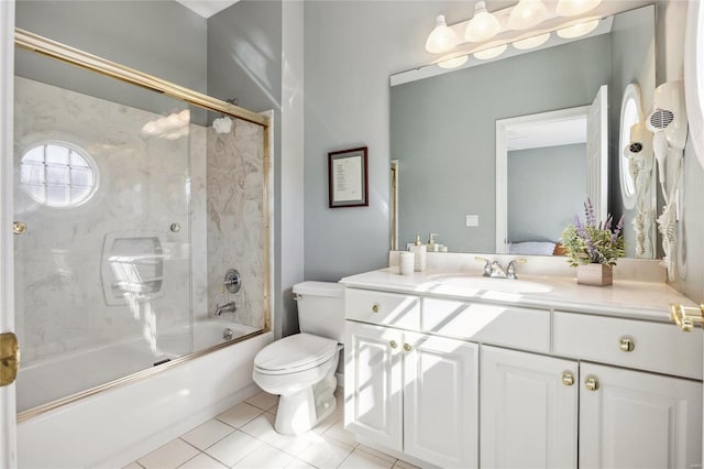 full bathroom featuring tile patterned flooring, vanity, toilet, and bath / shower combo with glass door