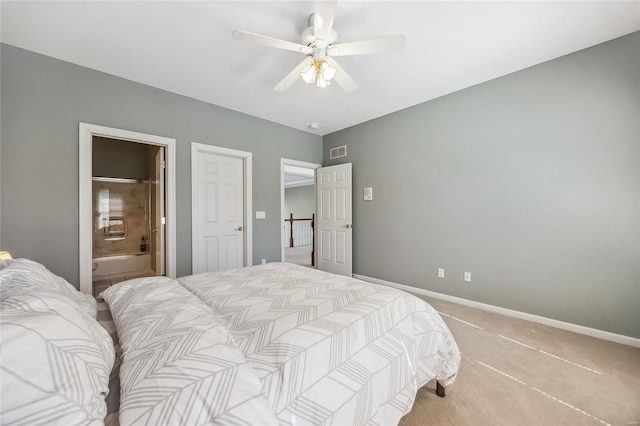 bedroom with baseboards, visible vents, light colored carpet, ensuite bath, and ceiling fan