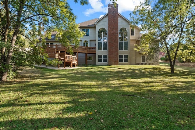 back of property with a chimney, a deck, and a yard