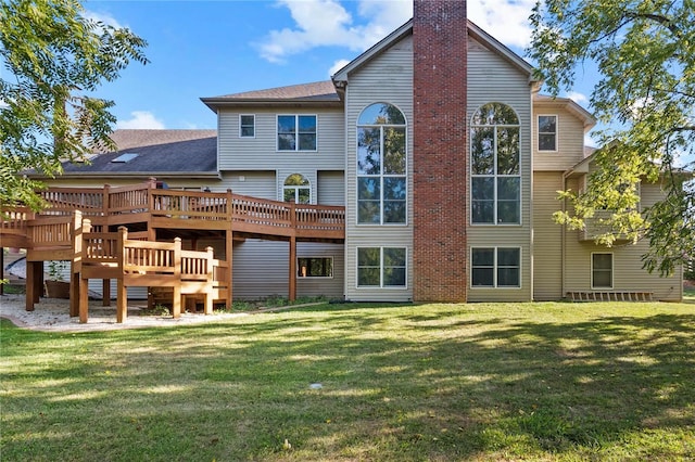 rear view of property with a chimney, a lawn, and a wooden deck