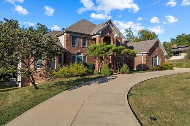 view of front of property featuring central air condition unit, brick siding, driveway, roof with shingles, and a front yard