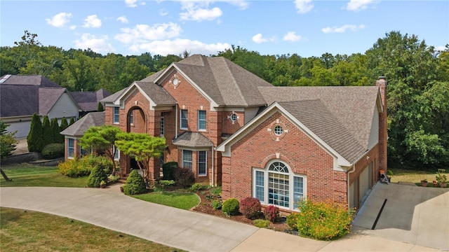 view of front of home featuring a garage, brick siding, driveway, a chimney, and a front yard