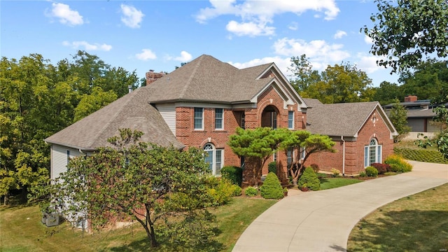 view of front of house with a chimney, a front lawn, and brick siding