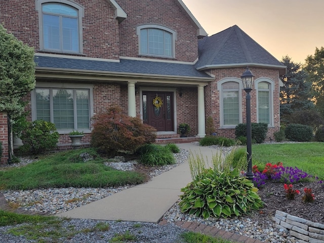 view of front of home featuring brick siding and roof with shingles