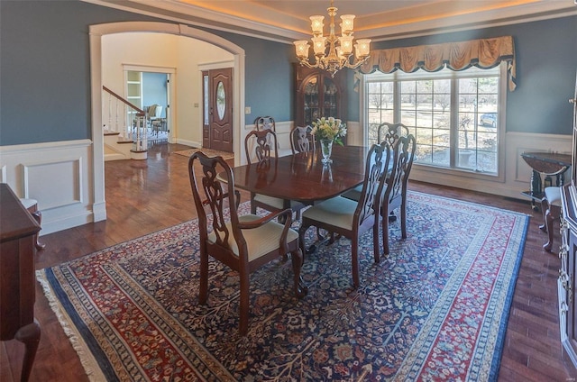 dining space with arched walkways, a wainscoted wall, a chandelier, and wood finished floors