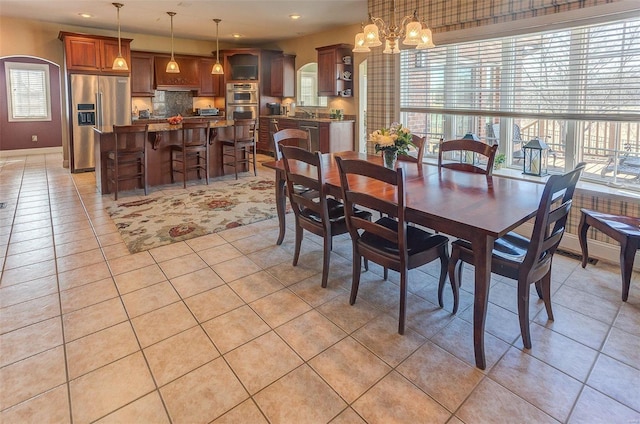 dining space with recessed lighting, arched walkways, an inviting chandelier, light tile patterned floors, and baseboards