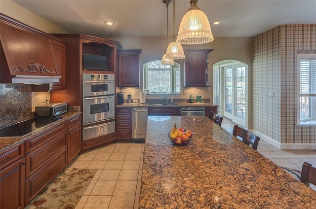 kitchen featuring wallpapered walls, arched walkways, stainless steel appliances, a warming drawer, and a sink