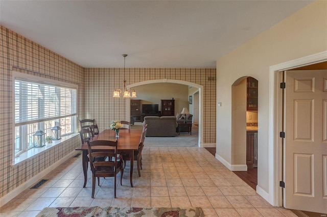 dining area featuring visible vents, arched walkways, light tile patterned flooring, wallpapered walls, and a chandelier