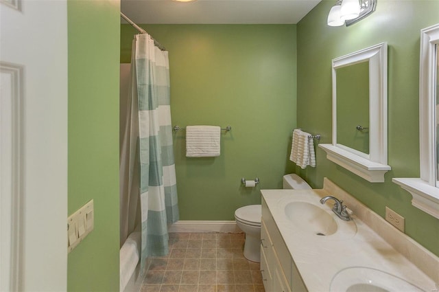 bathroom with visible vents, baseboards, double vanity, a sink, and toilet