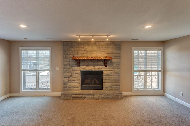 unfurnished living room featuring recessed lighting, a stone fireplace, carpet flooring, and baseboards