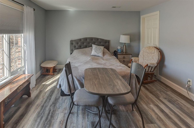 bedroom featuring visible vents, baseboards, and wood finished floors