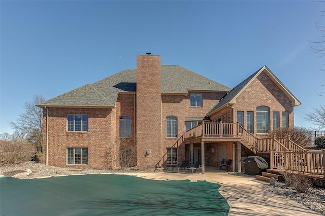 rear view of property featuring stairway, a patio, brick siding, and a chimney