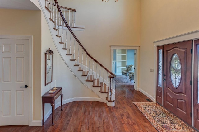 entrance foyer featuring stairway, wood finished floors, baseboards, and a towering ceiling