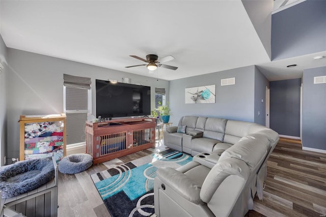 living area featuring baseboards, wood finished floors, visible vents, and a ceiling fan