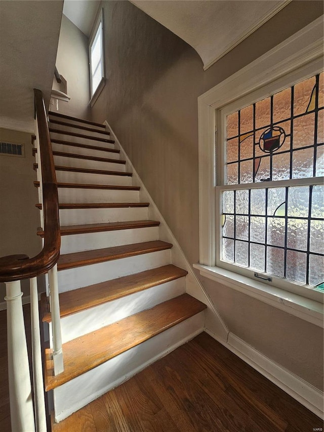 stairs featuring visible vents, baseboards, and wood finished floors