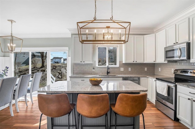 kitchen with tasteful backsplash, a kitchen bar, ornamental molding, an inviting chandelier, and stainless steel appliances